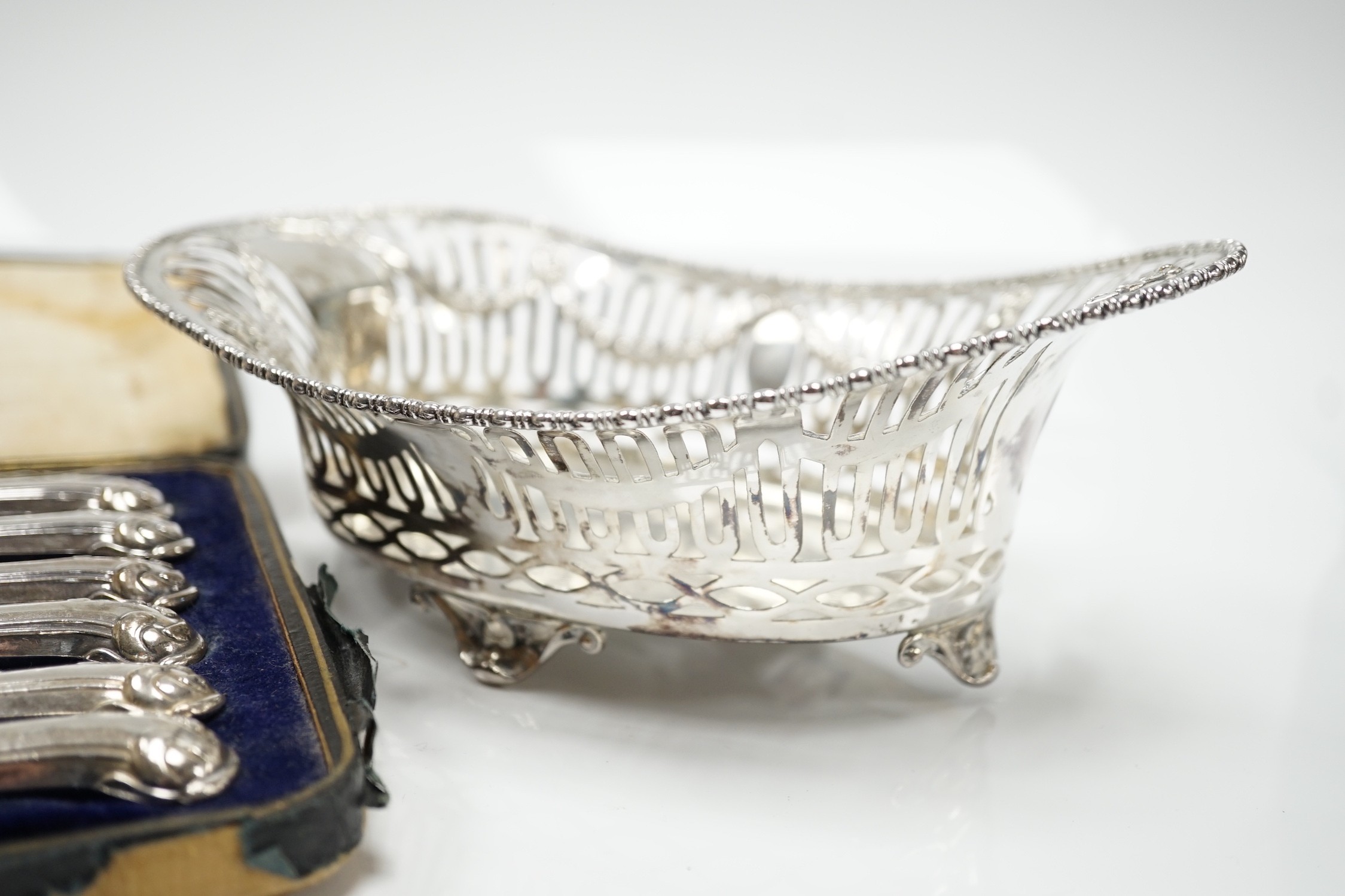 A George V pierced silver oval bowl, 21cm, London, 1912, 5.5oz and a cased set of six silver pistol handled steel tea knives.